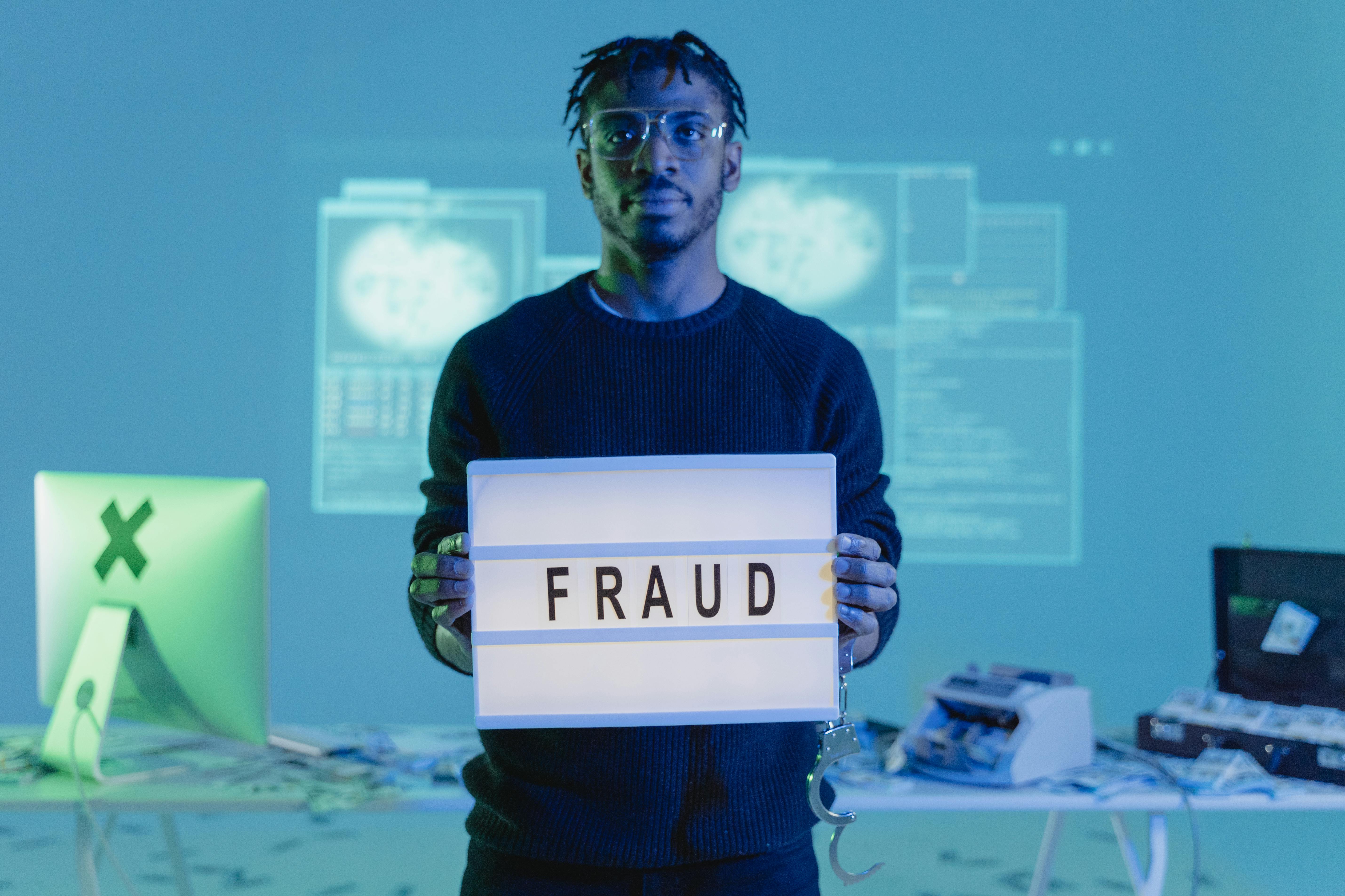 Man holding fraud sign with computer in the background